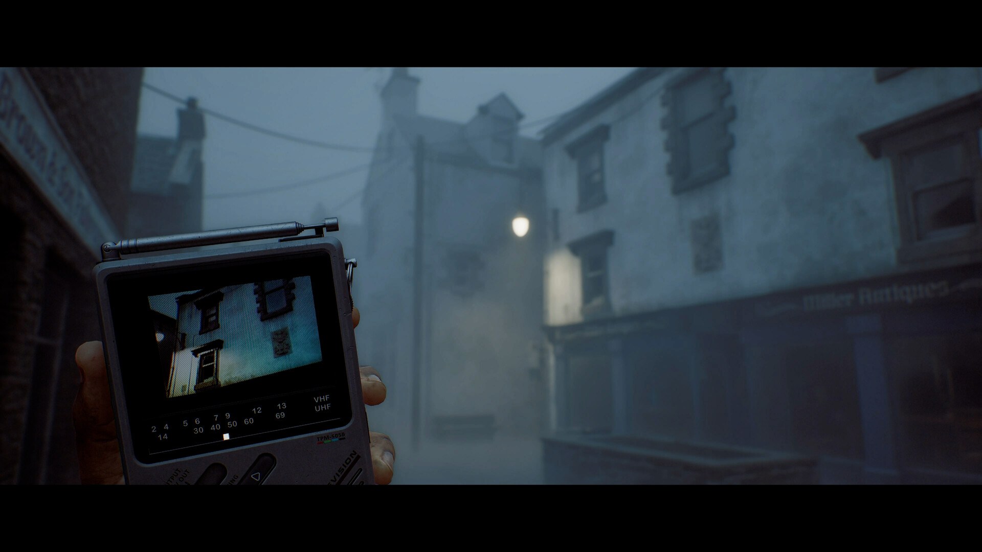The CRTV handheld television held up against a foggy street in SILENT HILL: Townfall